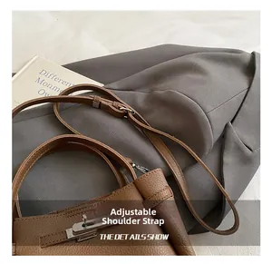 Detail of brown litchi leather bag showing silver metal twist lock and adjustable strap
