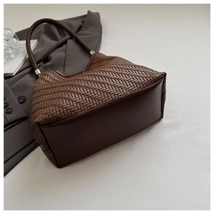 Detail of dark brown woven tote bag showing premium leather texture and braided handle
