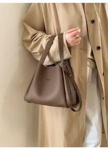 Deep brown lychee textured leather bucket bag styled with a beige long trench coat