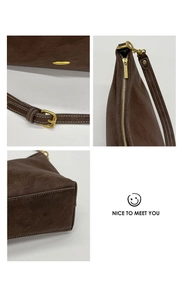 Detail view of dark brown faux leather bag with gold-tone hardware and adjustable strap