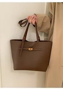 Detail of a brown leather tote bag featuring a polished gold metallic turn-lock closure