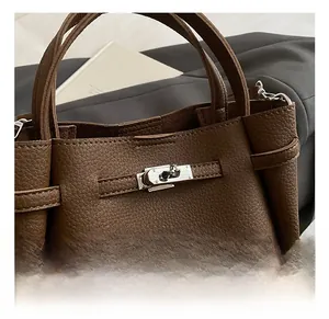 Detail of silver twist lock and litchi grain leather texture on brown bucket bag