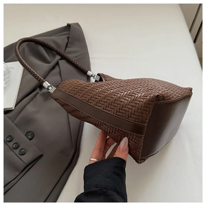 Detail view of woven brown leather bucket bag with silver hardware and shoulder strap