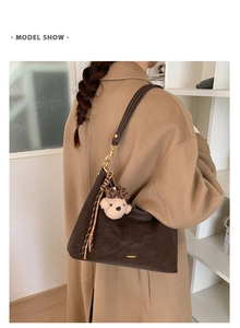 Detail of dark brown baguette bag in soft matte leather with cute plush bear charm