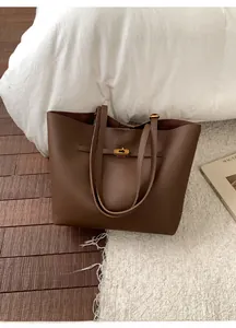 Detail of dark brown lychee leather texture and golden metal twist lock on a tote bag