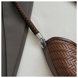 Close-up of dark brown woven leather bucket bag with silver metal hardware and straps