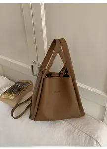 Close-up of brown litchi pattern bucket bag with adjustable strap on white fabric