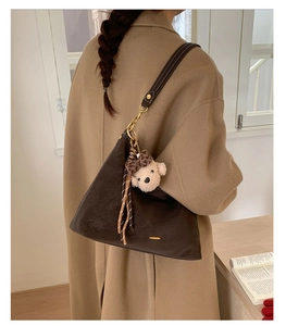 Deep brown leather hobo bag with a cute bear plush pendant and adjustable wide strap