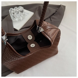 Detail of deep brown woven bucket bag showing silver magnetic closure and interior lining