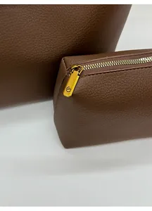 Detail of a brown lychee pattern leather pouch with vintage gold hardware and GM logo zipper