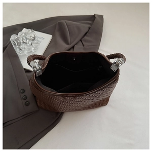 Detail view of woven brown bucket bag with magnetic closure and internal zipper pocket