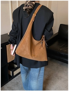 Detail van een bruine suède hobo tas met gouden gesp en een kralen kwastje decoratie