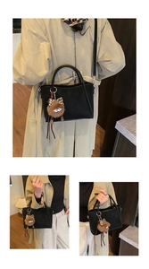 Detail of matte black suede bucket bag with adjustable strap and plush monster charm