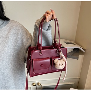 Detailed view of dark red leather tote bag featuring two front magnetic pockets and plush bear