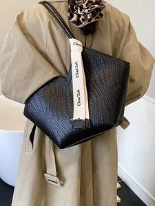 Sac cabas tissé en cuir noir avec bandoulière contrastée et ouverture en V porté sur trench
