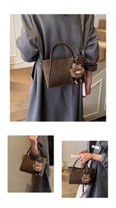 Detail of soft suede bucket bag with adjustable strap and cute plush monster charm