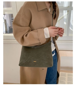 Olive green matte shoulder bag with gold hardware worn with an elegant cashmere coat