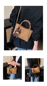 Close-up of brown leather bucket bag with a leopard bow plush monster charm