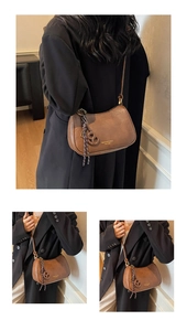 Detail view of a brown vintage crescent bag with adjustable strap and brand logo print