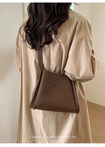 Detail of vintage dark brown pebbled leather bucket bag styled on a female model