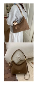 Detail of dark brown matte hobo bag with gold hardware and plush bear charm