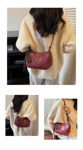Detail view of burgundy half-moon crossbody bag with leather texture and gold hardware