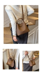 Dettaglio di una borsa a secchiello marrone in pelle con motivo litchi e tracolla