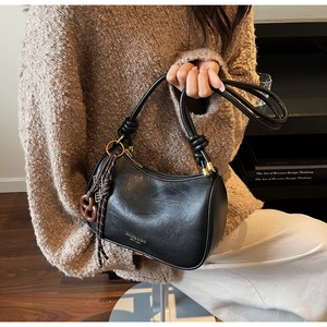 Close-up of black leather crescent bag with knotted handle and gold hardware detail