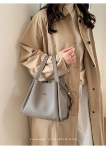 Detail of grey pebble leather tote bag with shoulder strap and minimalist metal branding