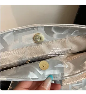 Detail of silver handbag featuring a secure magnetic buckle and zippered inner pocket