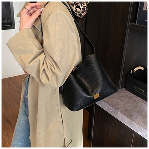 Détail d'un sac seau en cuir grainé noir avec plaque dorée et fine bandoulière