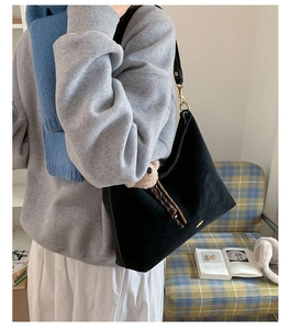 Detail of black suede tote bag with white stitching and cute brown bear pendant