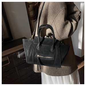 Detail einer schwarzen matten Ledertasche mit goldener Hardware auf einem Schrank