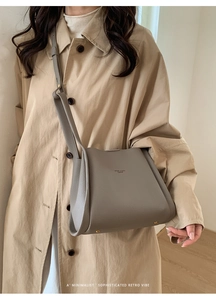 Detail of taupe lychee leather bucket bag showing golden feet and adjustable strap
