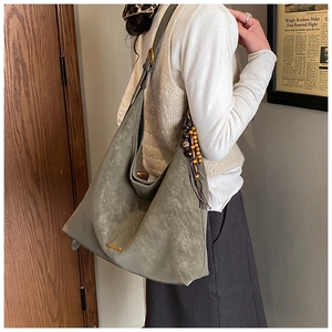 Detail showing high-capacity grey hobo tote bag with a wooden bead and leather tassel charm