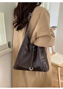 Détail du sac hobo en cuir marron foncé avec surpiqûres blanches et anneau argenté