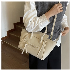 Model trägt eine cremefarbene Muscheltasche mit Quasten und Seitenflügeln auf Treppen
