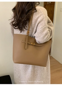 Brown lychee leather tote bag with gold buckle details worn by model in a minimal setting