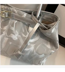 Detail of silver grey handbag with letter jacquard pattern and gold horseshoe buckle