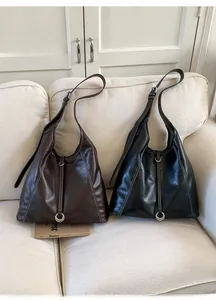 Détail de sacs cabas vintage en cuir huilé avec coutures contrastées et boucles métal