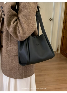 Detail of black pebbled leather bucket bag with brand logo and textured material