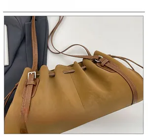Detail of caramel pleated bucket bag showing drawstring closure and lychee grain leather