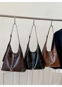 Détail de sacs cabas vintage marron et noir avec surpiqûres blanches et boucle métallique