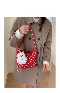 Détail du sac à main rouge à pois blancs en toile avec un charmant chien en peluche blanc