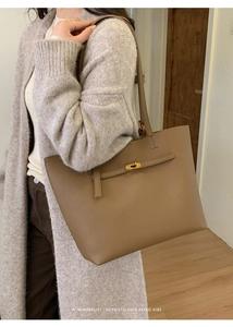 Detailed view of brown leather tote bag featuring a gold twist-lock closure and slim straps