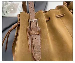 Detail view of the silver metal buckle and adjustable brown leather strap on the tote bag
