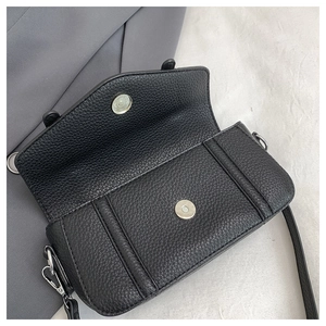 Detail of black lychee grain leather crossbody bag with magnetic buckle and silver hook