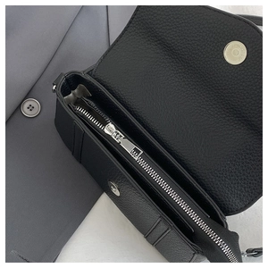 Close-up of black lychee leather bag with silver magnetic buckle and zip compartment