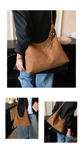 Detail van een bruine suède hobo tas met Boheemse kwastjes en houten kralen decor