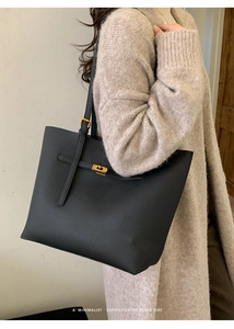 Detail of black pebbled leather tote with golden cross lock buckle and adjustable strap